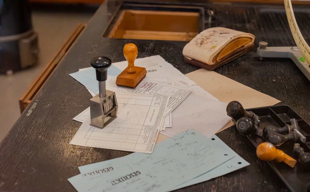 Mesa de escritório com documentos variados e carimbos sobre os papéis.
