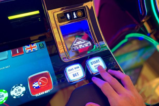 Mão interage com botões de uma interface digital colorida de máquina caça-níquel.