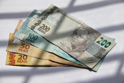 Cédulas de real brasileiro dispostas sob a luz do sol.